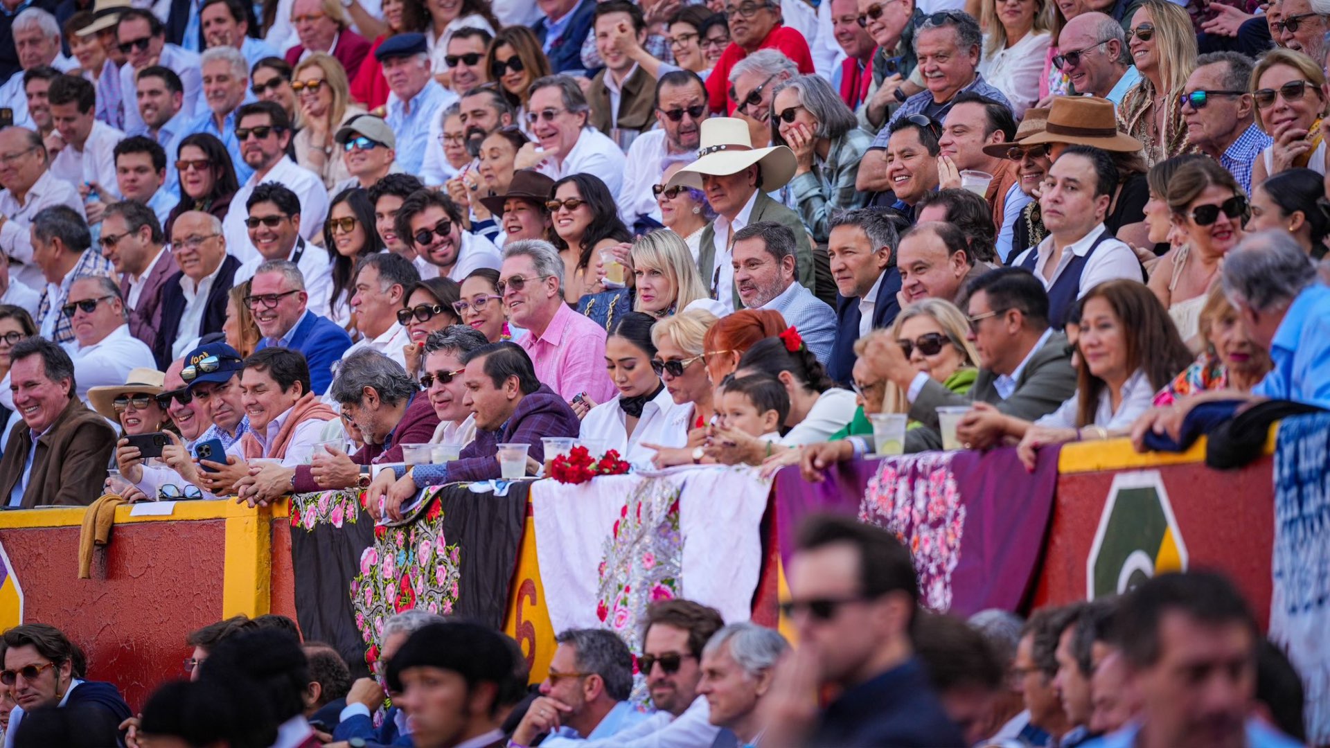 Público de Acho vestido de blanco con mantones bordados en la barrera