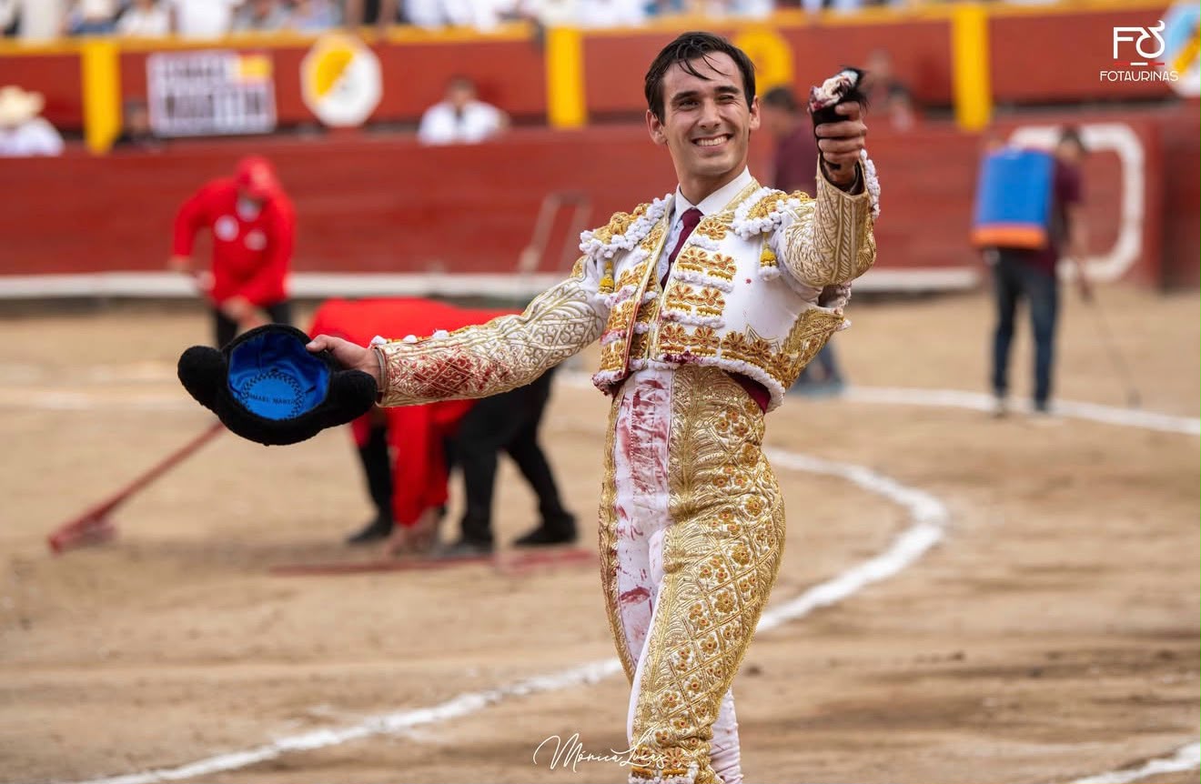 Torero sonriente muestra la oreja con la montera en la mano en el ruedo de Acho